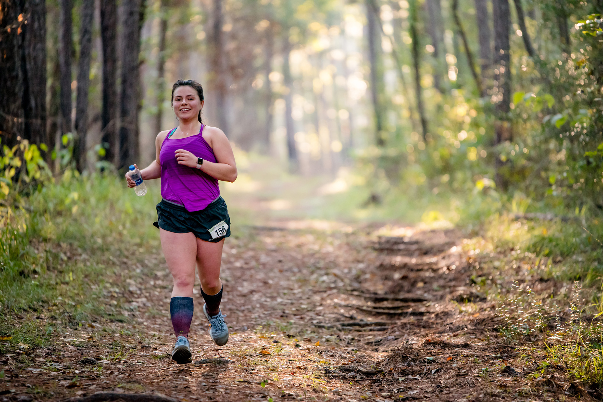 a woman runs through an East Texas forest trail