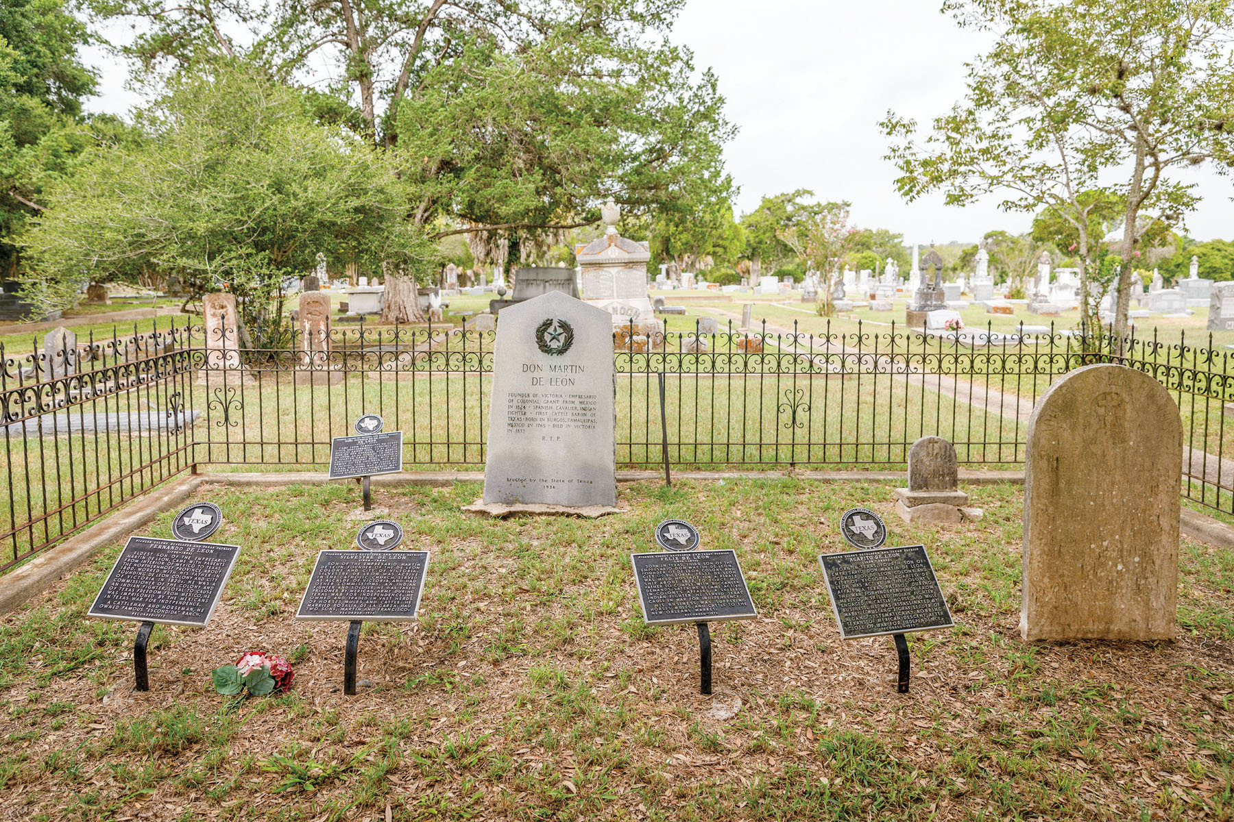 A cemetary with several black plaques and concrete headstones