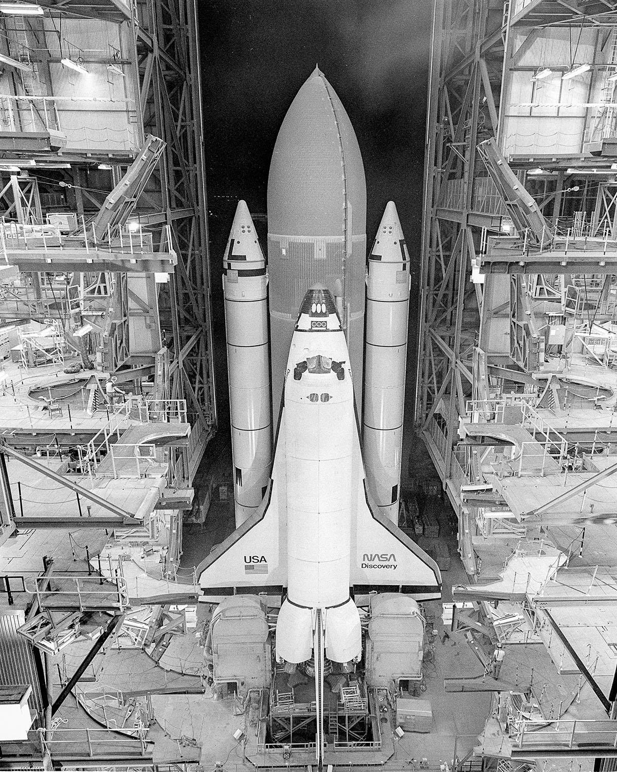 A black and white photo of Space Shuttle Discovery attachhed to launch gear