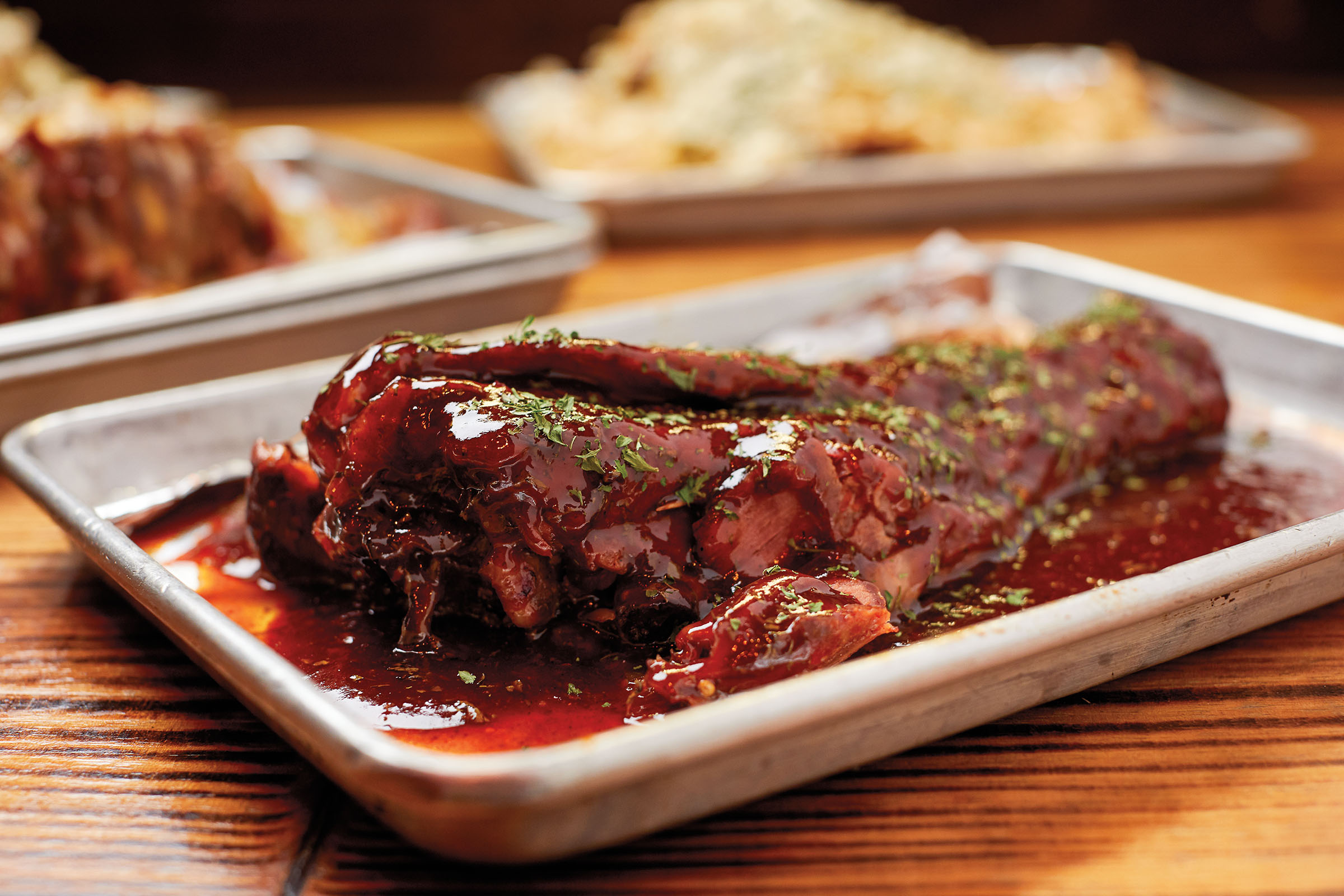 A turkey leg on a small silver tray covered in a brown-red Hennesy sauce