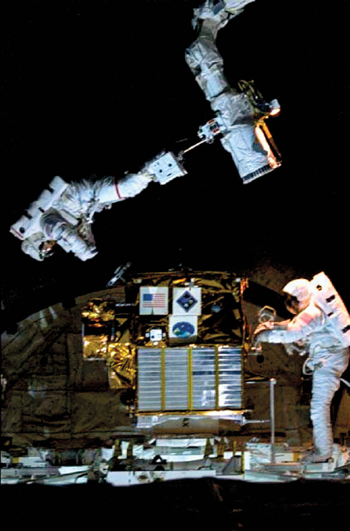 Two astronauts use a tool with a sattelite in the background