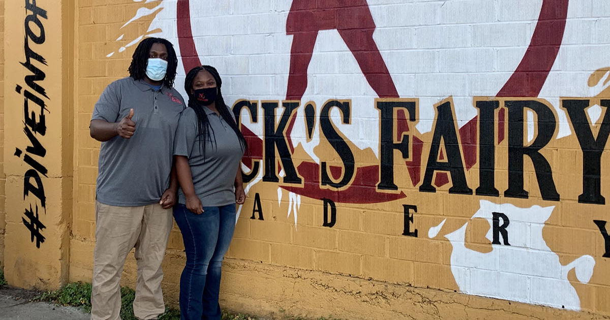 Black's Fairy Meadery co-owners Calvin Greene and Terica Groves photographed at their meadery, standing next to a mural on the outside of the building.