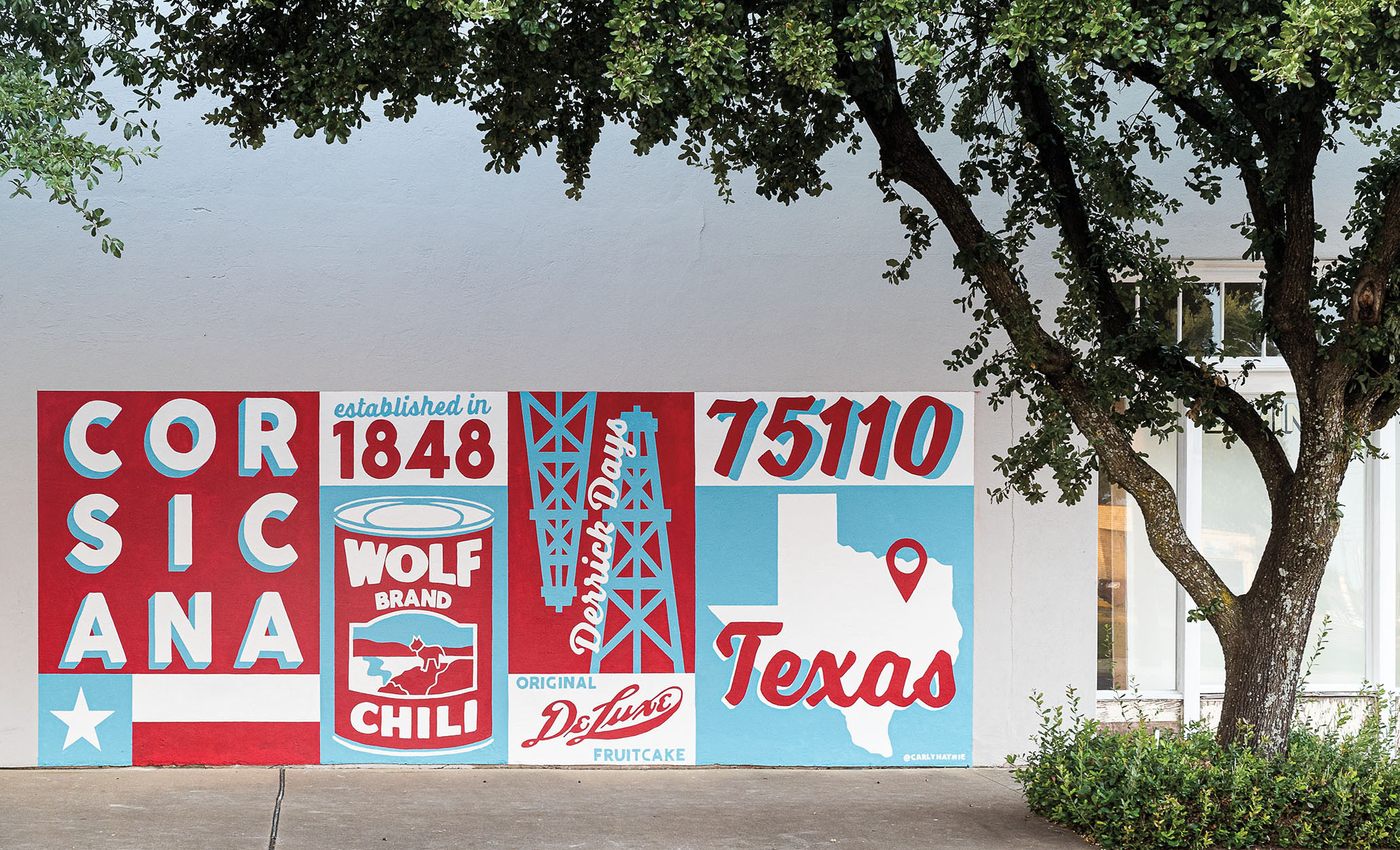 A red, white and blue mural in the town of Corsicana referencing history as birthplace of Wolf Brand Chili. Mobil Oil, and Collin Street Bakery