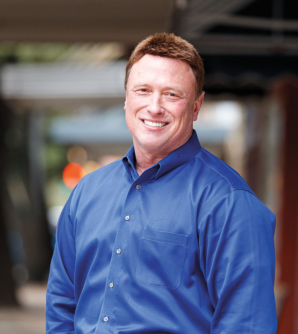 A man in a blue shirt smiles on a downtown Corsicana sidewalk