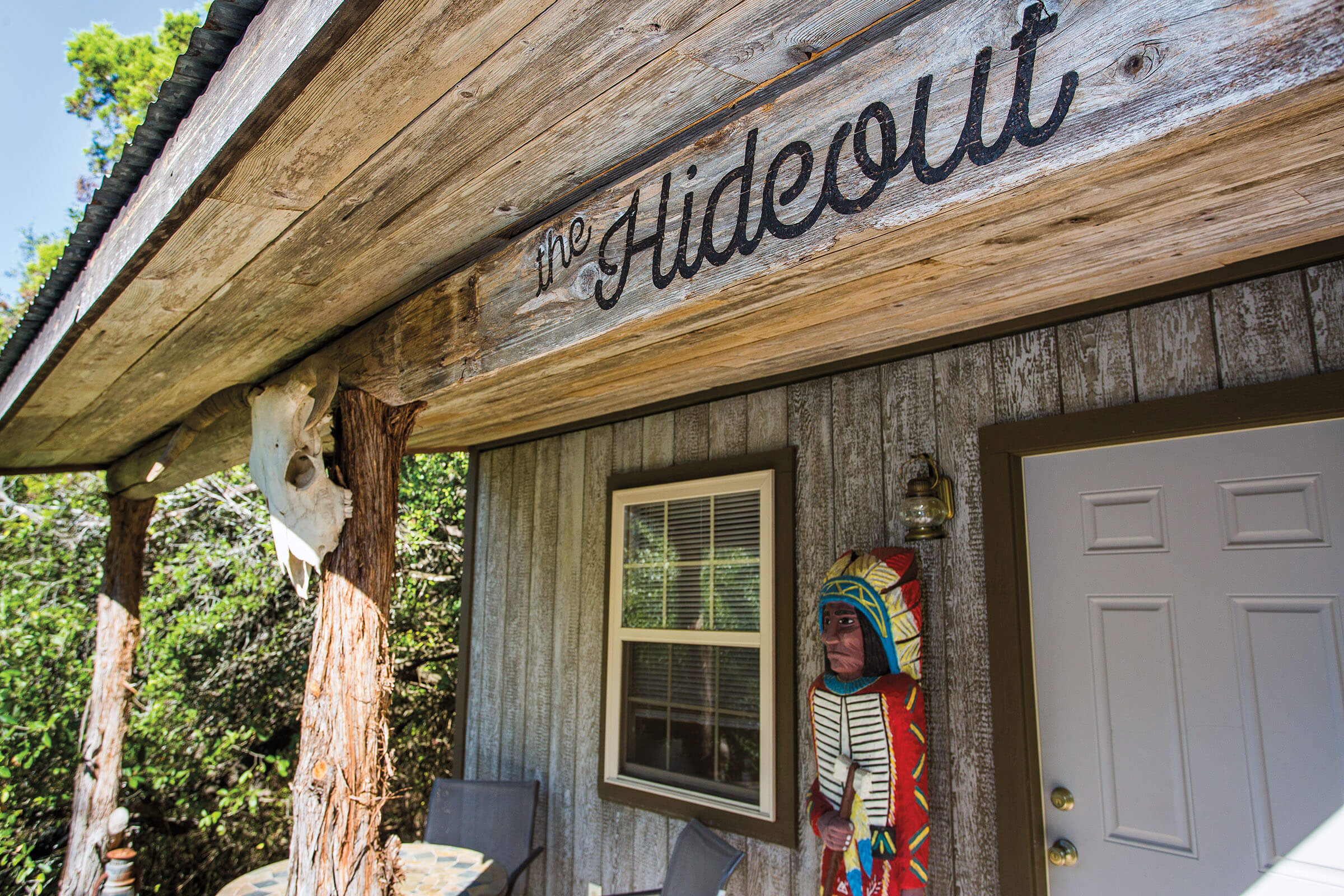 The outside of a wooden cabin reading "The Hideout"