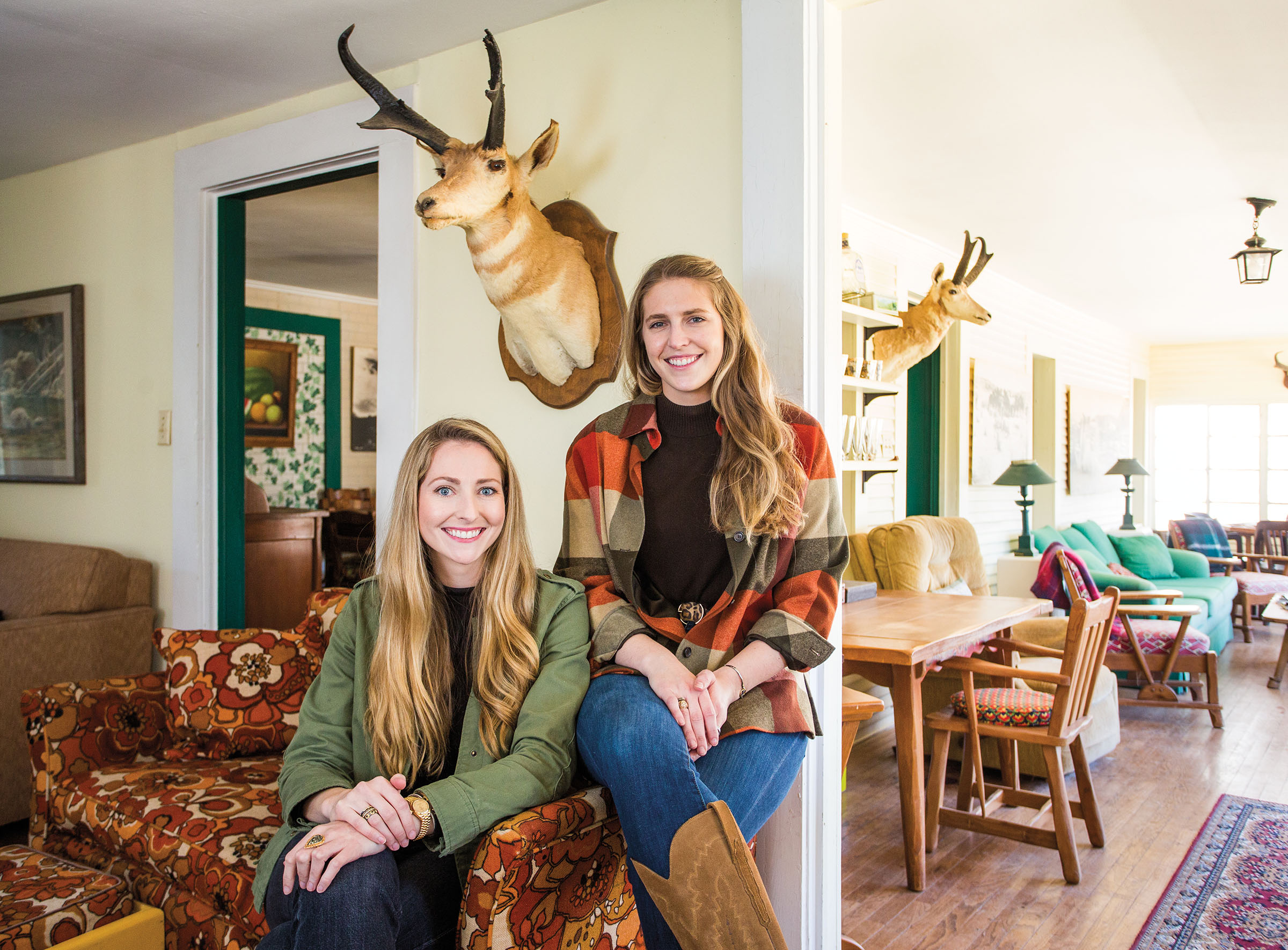 Two women sit beneath a mounted antelope head on the wall of the Hudspeth River Ranch
