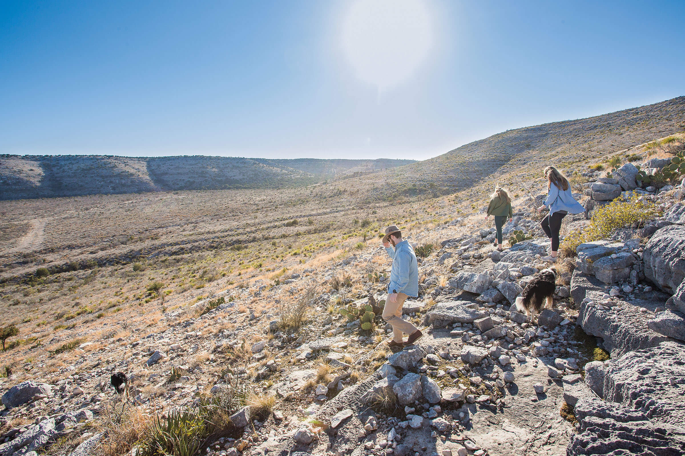 A group of people walk through a rocky desert terrain