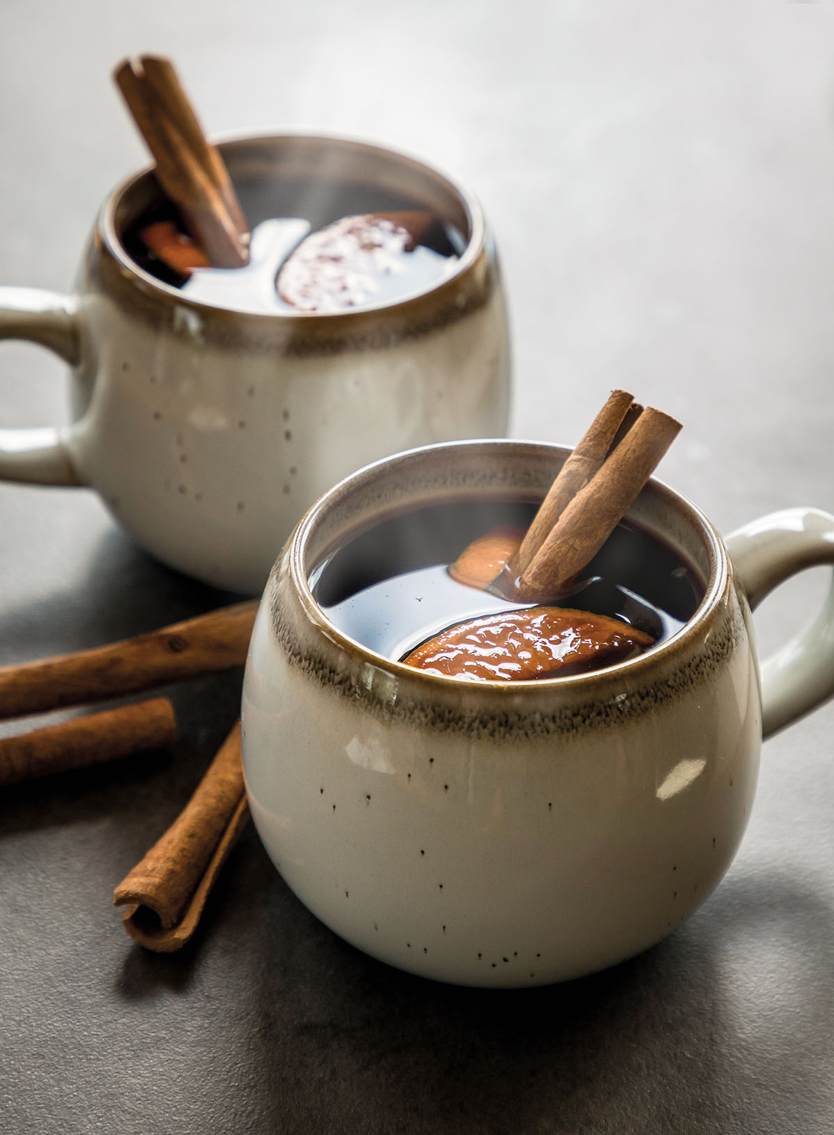 Two mugs of gluhwein with cinnamon sticks in stoneware