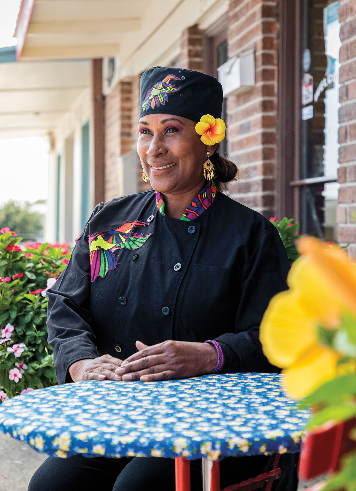 A woman in a chef's uniform stands at a table