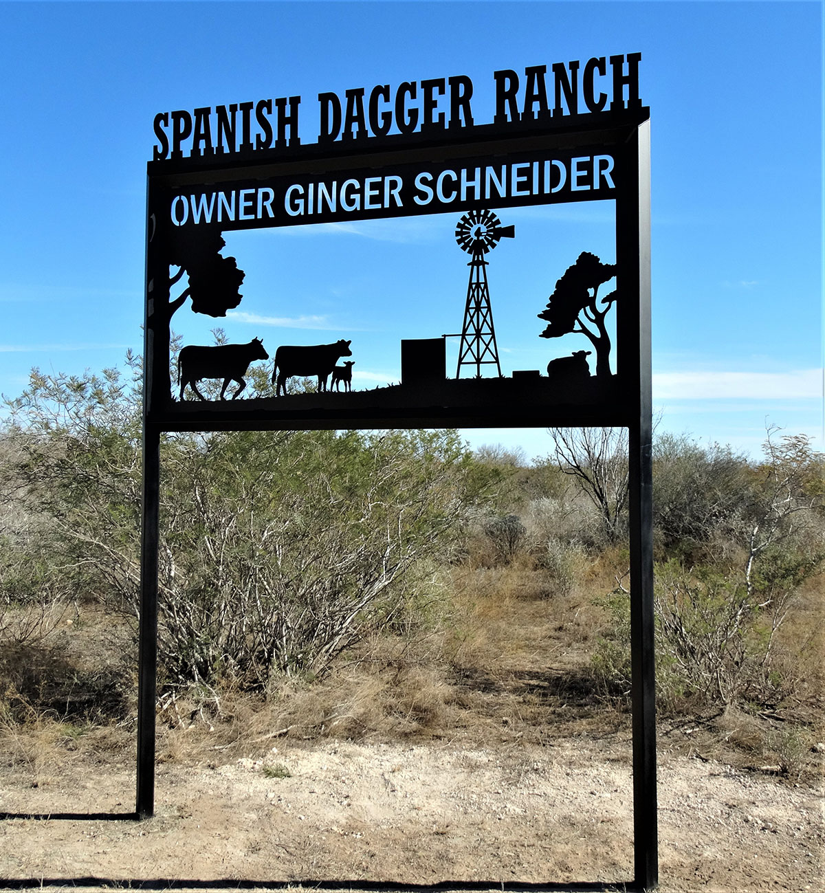 A metal works sign says Spanish Dagger Ranch, Owner Ginger Schneider located outside. 