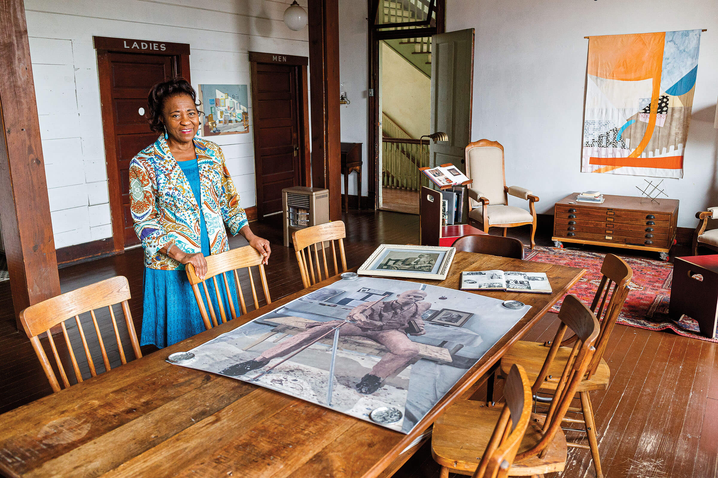 A woman stands behind a table with photographs