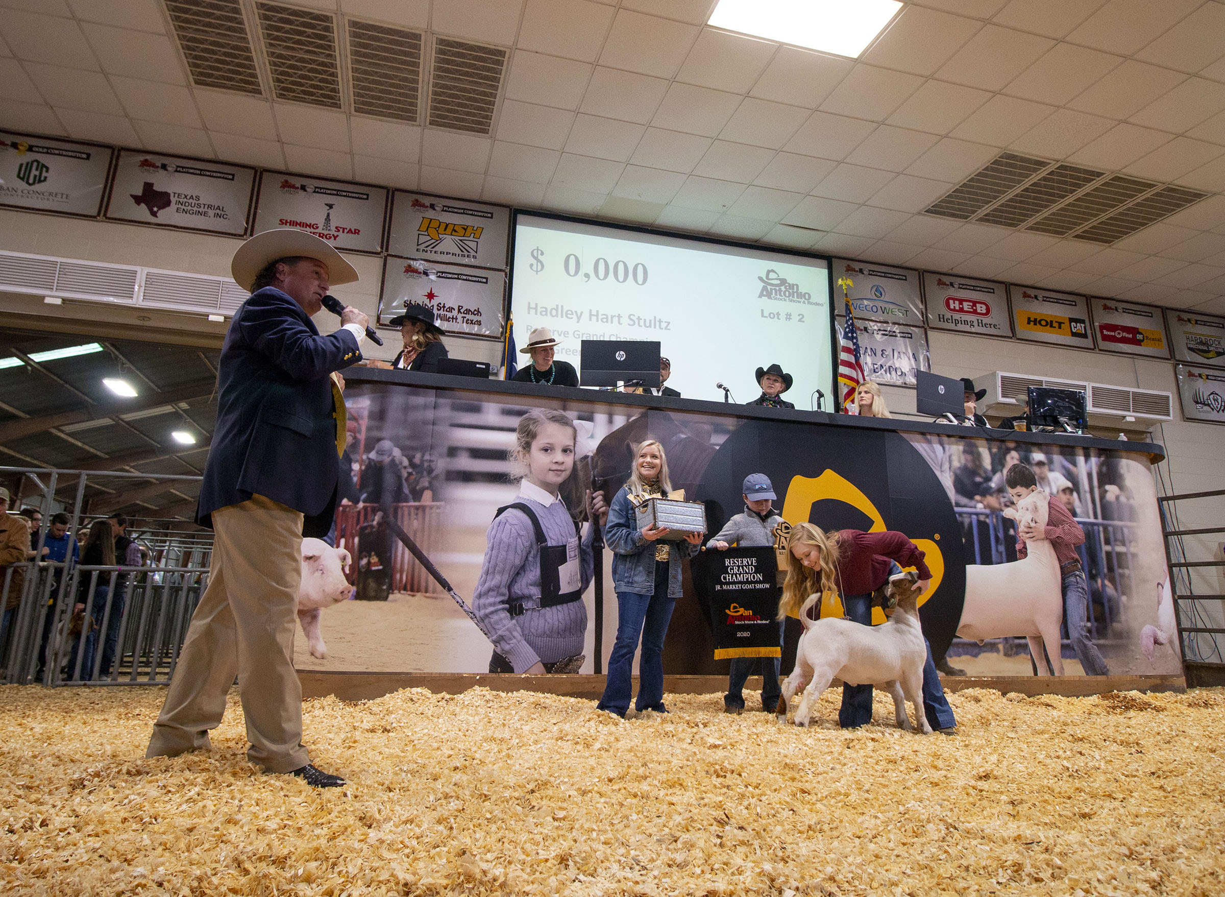 Auctioneer C. Jason Spence calls a goat auction at the San Antonio Livestock Show, with kids in the background. Photo courtesy of San Antonio Stock Show and Rodeo.