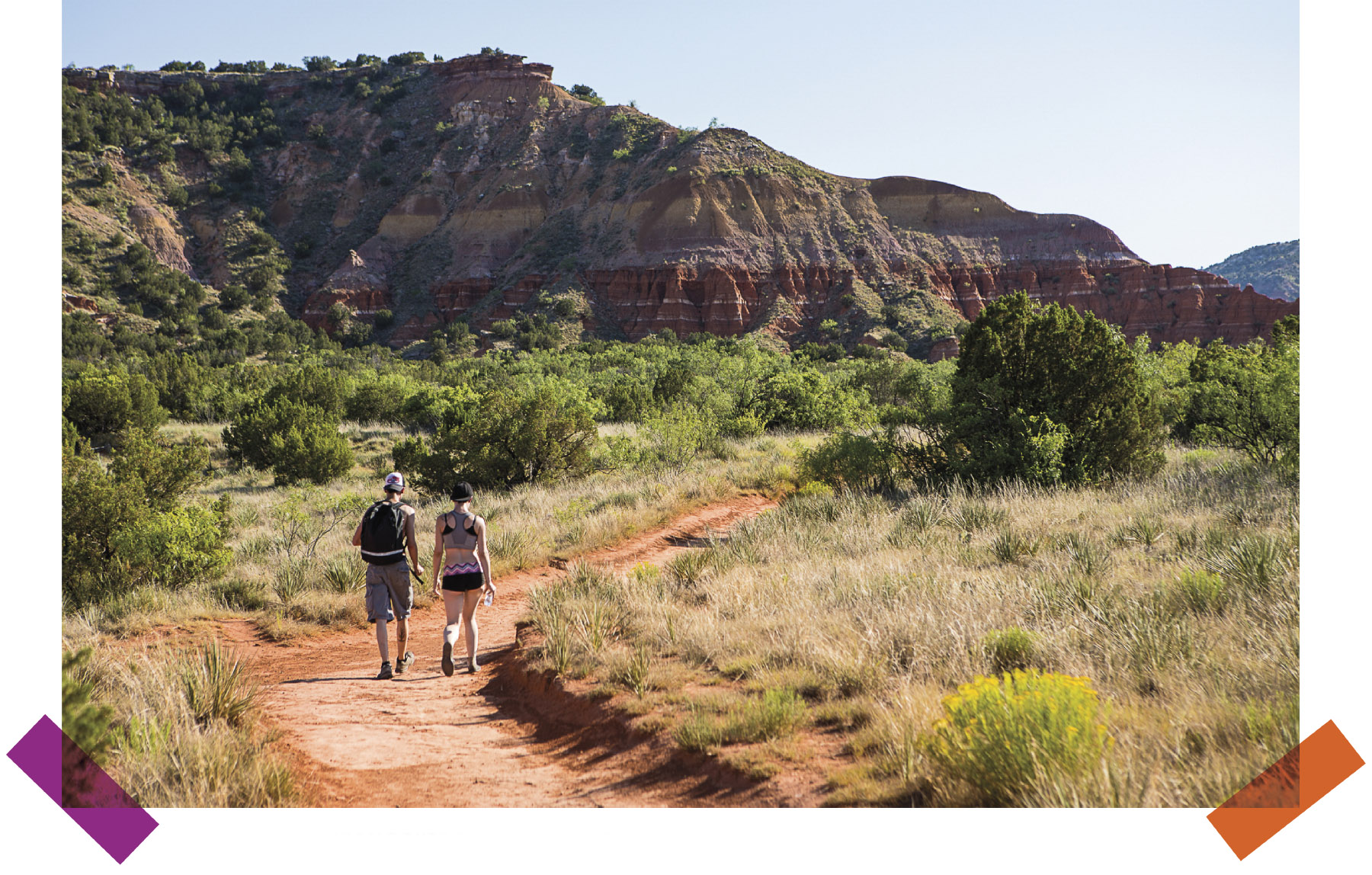 Two hikers walk down a dirt trail in Palo Duro