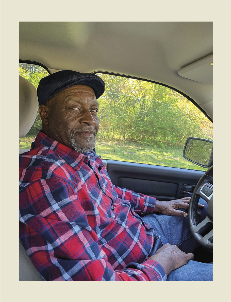 A man sitting in a car in a plaid shirt