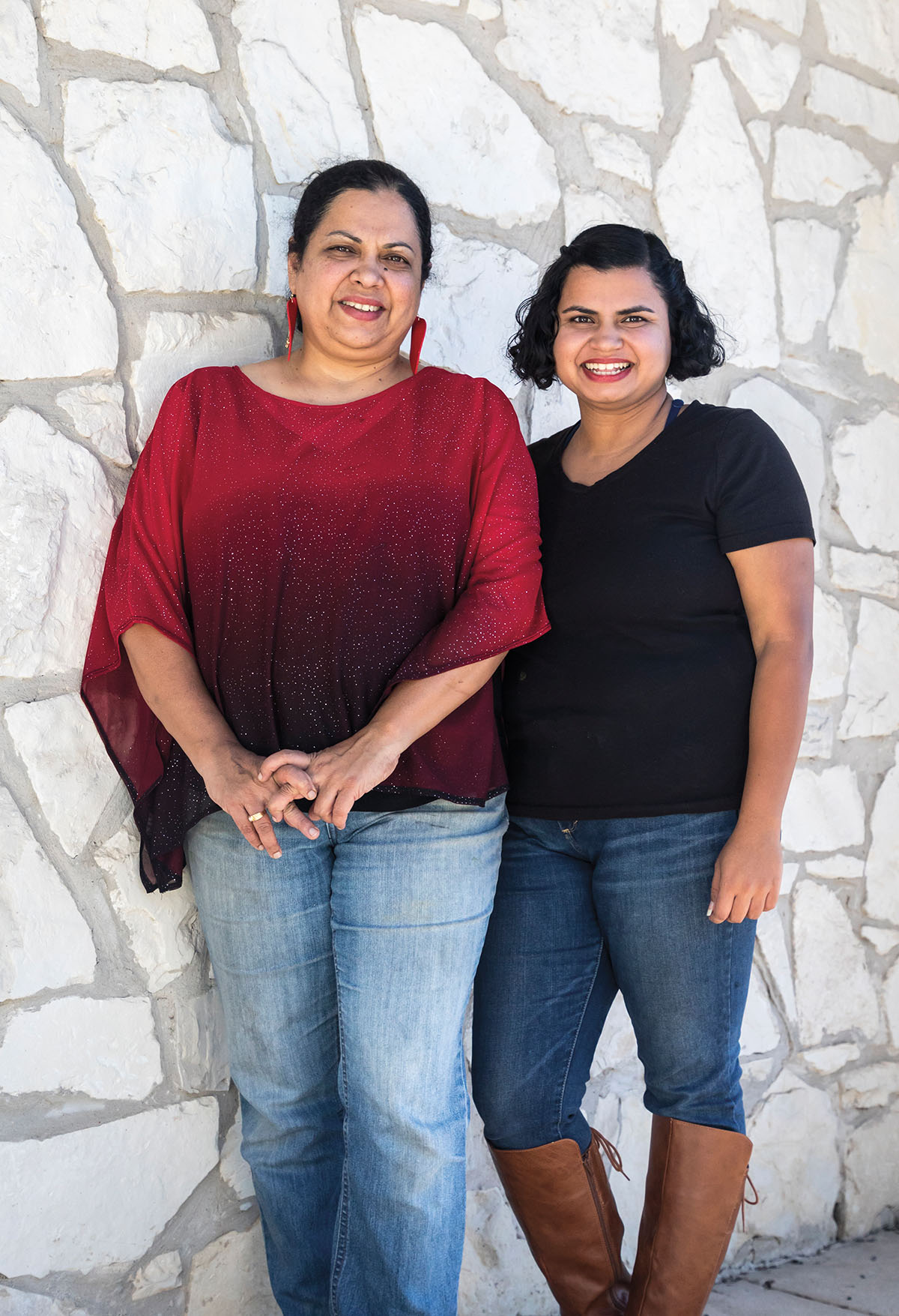 Two women stand in front of a white rock wall