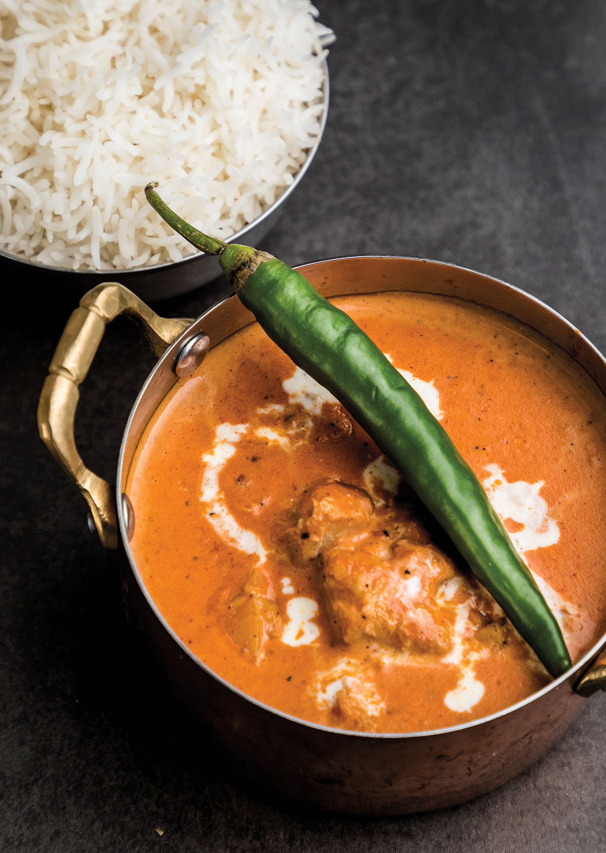 An overhead view of bright-orange Tikka Masala in a silver pot