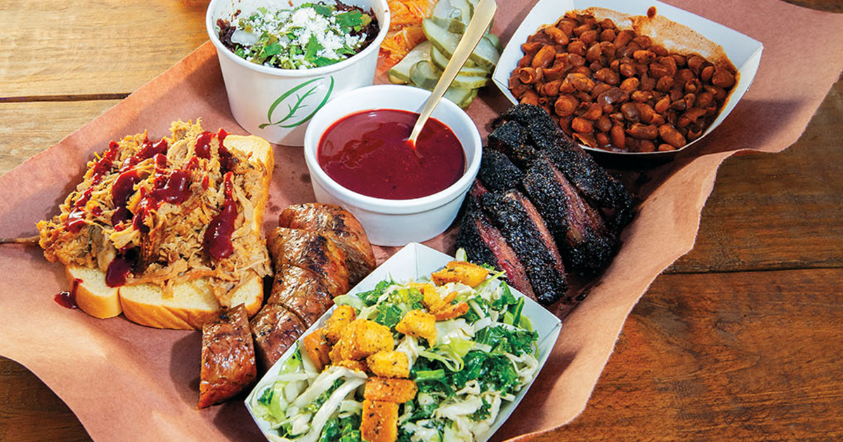 A platter of barbecue along with cup of bright purple sauce