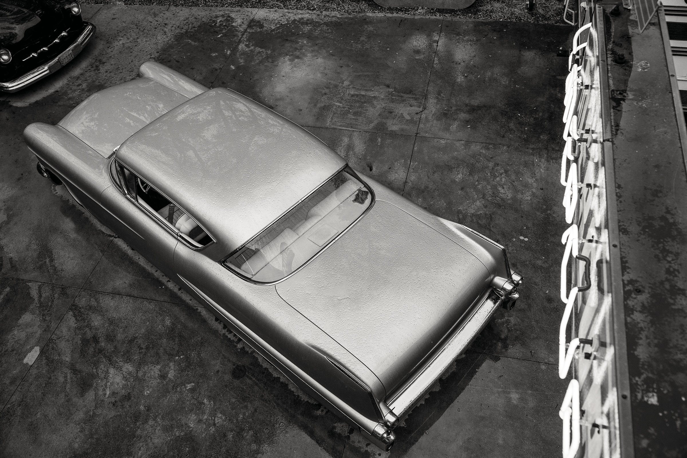 An overhead view of a Cadillac underneath a neon sign