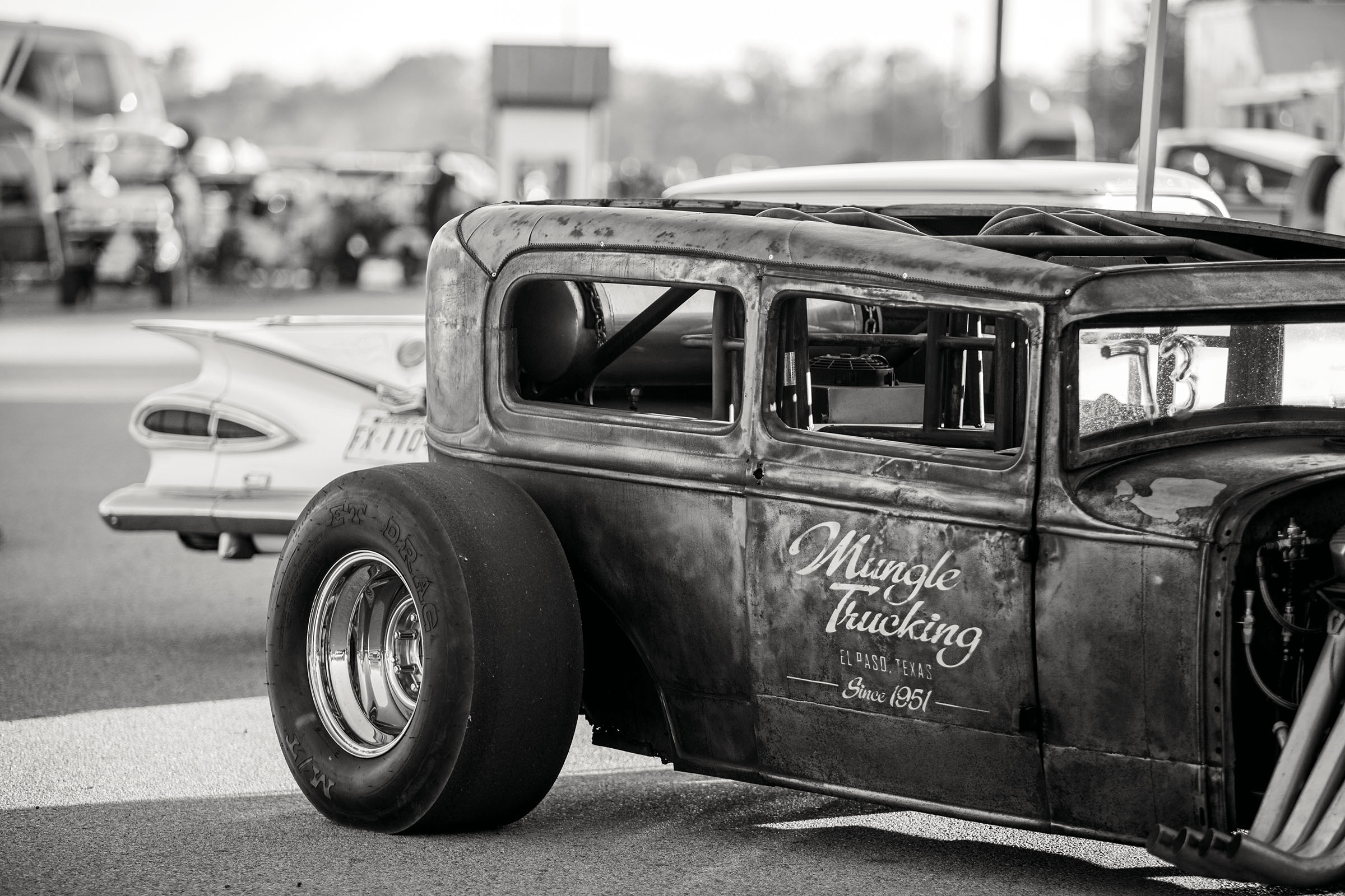 A black and white photo of an old car with a large wheel 