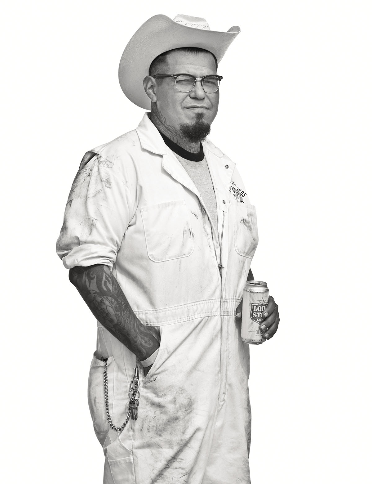 A man in a white cowboy hat stands with a Lone Star beer in his hand