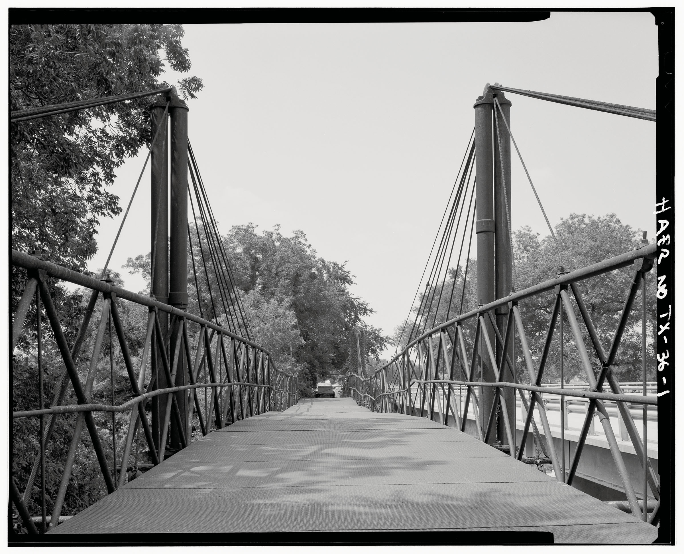 A black and white photo of a suspension bridge with a wide, flat crossing