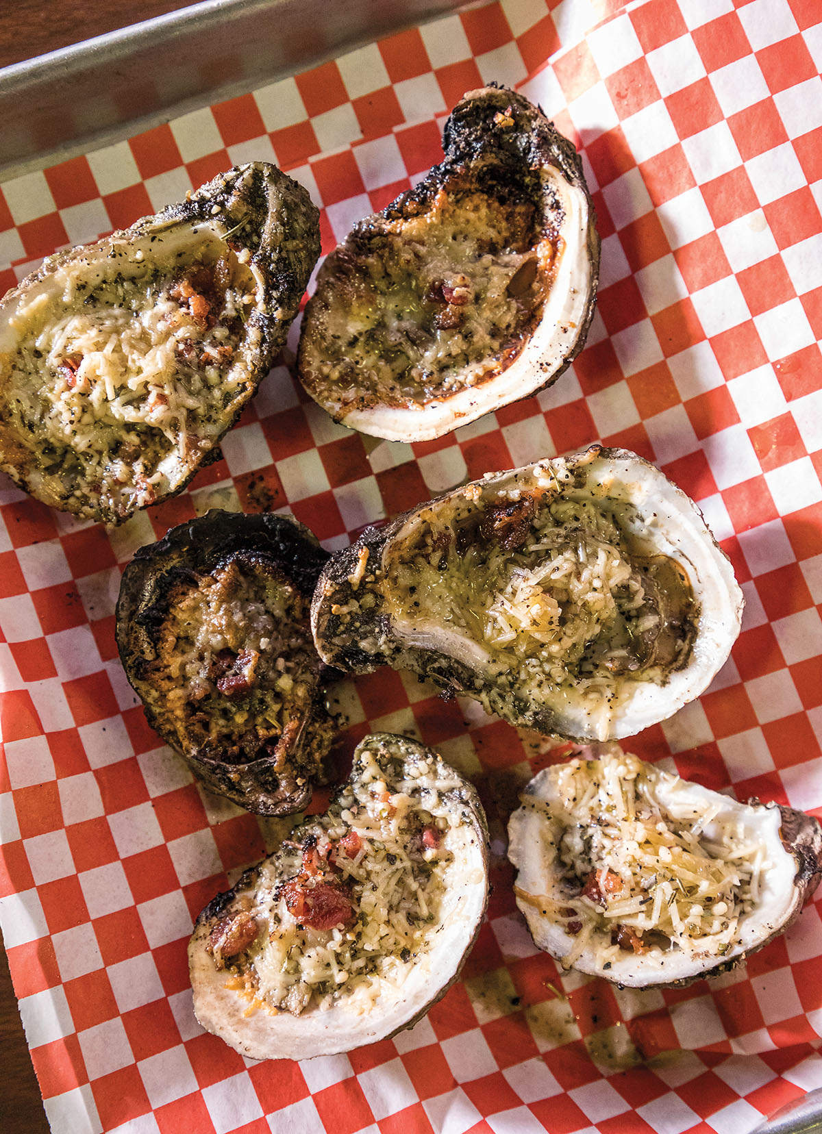 Six charbroiled oysters on a red checkered paper basket