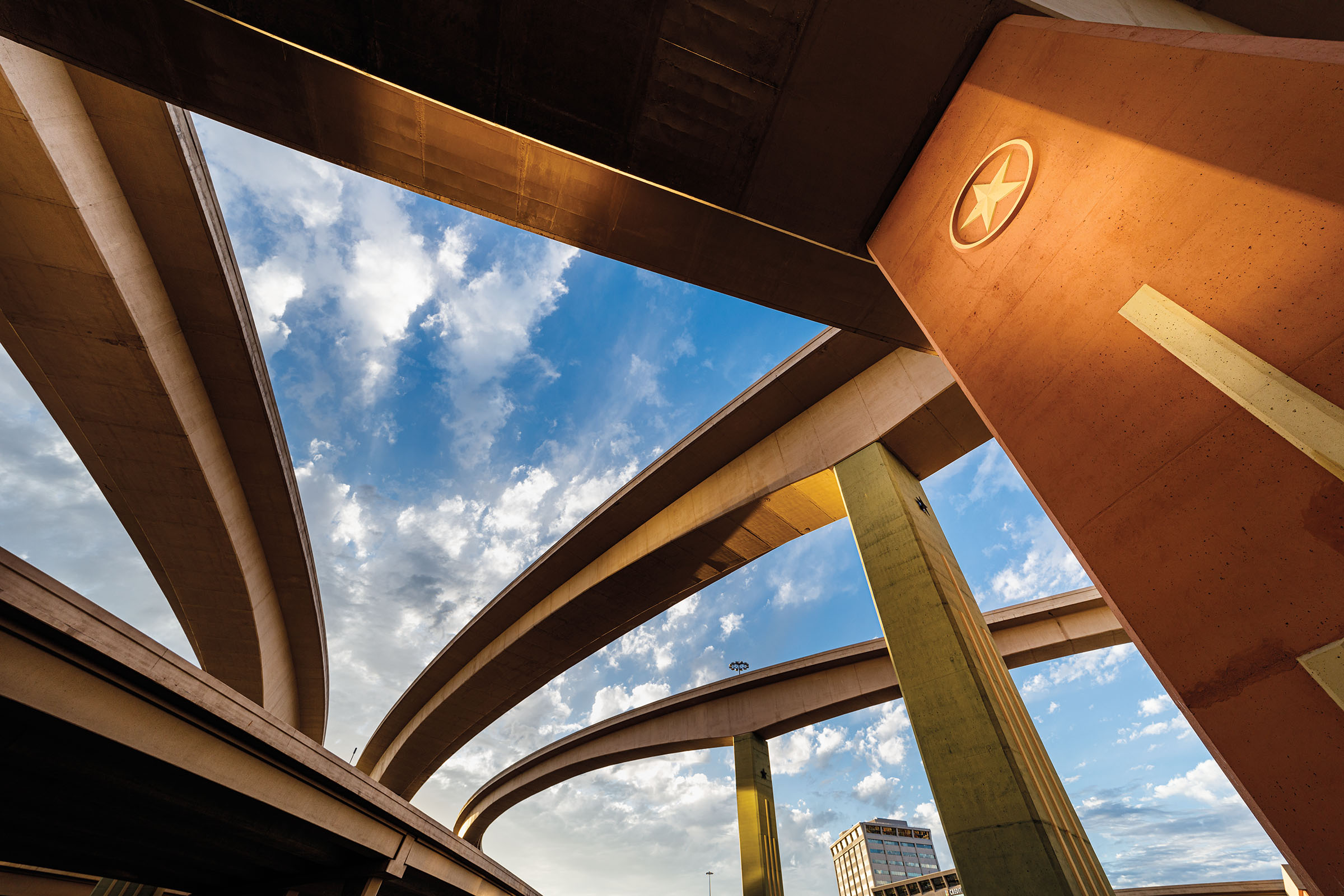 Tall, concreate overpasses and flyovers beneath a blue sky with clouds