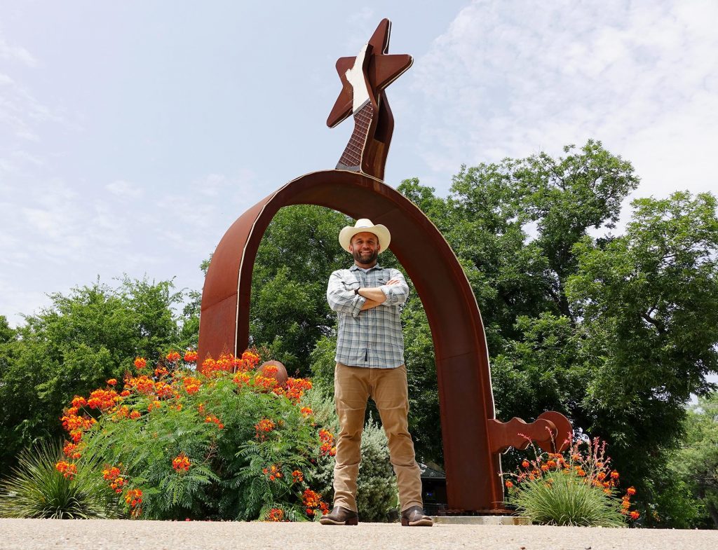 Daytripper host Chet Garner stands in front of the World's Largest Spur in Lampasas.