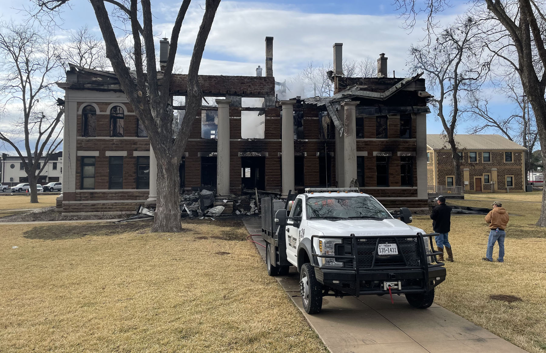 A white fire department truck parked out front of the burned remains of the Mason County Courthouse