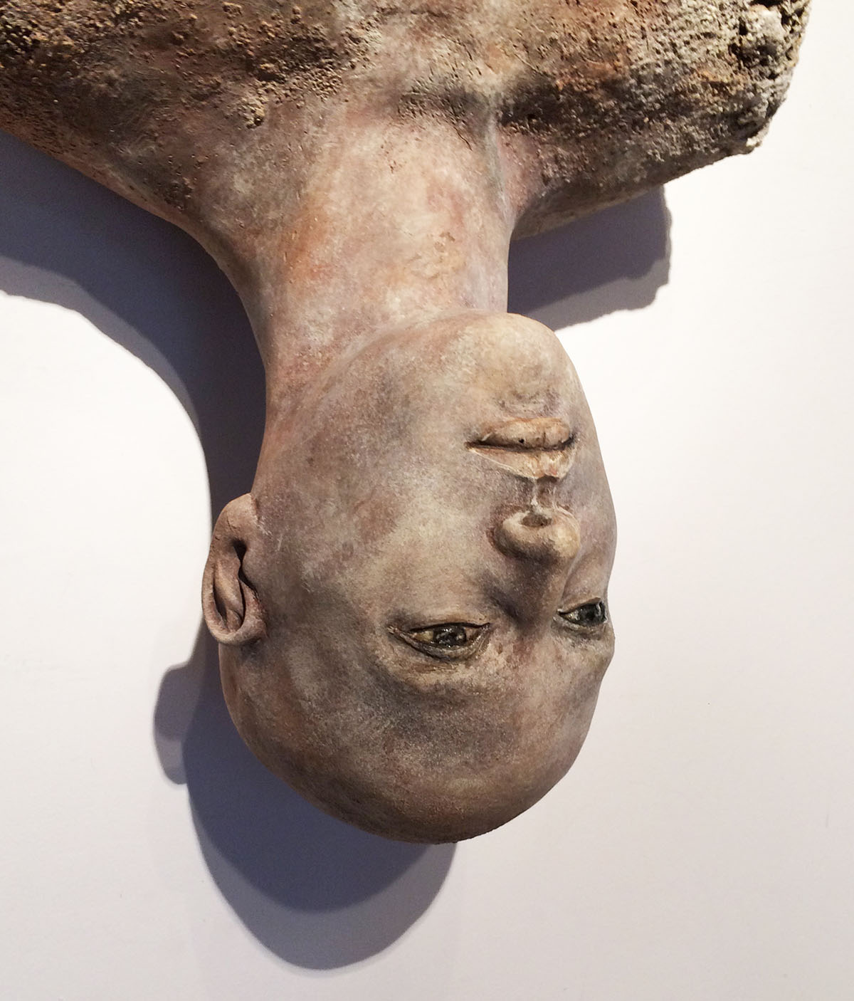 A clay sculpture by Alejandra Almuelle features the top half of a human figure hanging upside down, on display in 'The Many Shapes of Texas Clay.' Photo courtesy of the Rockport Center for the Arts.