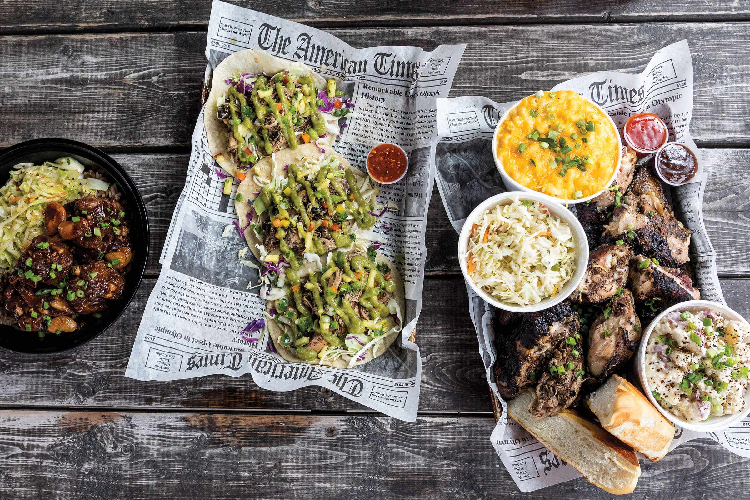 An overhead photo of plates of chicken and tacos on newsprint-lined plates