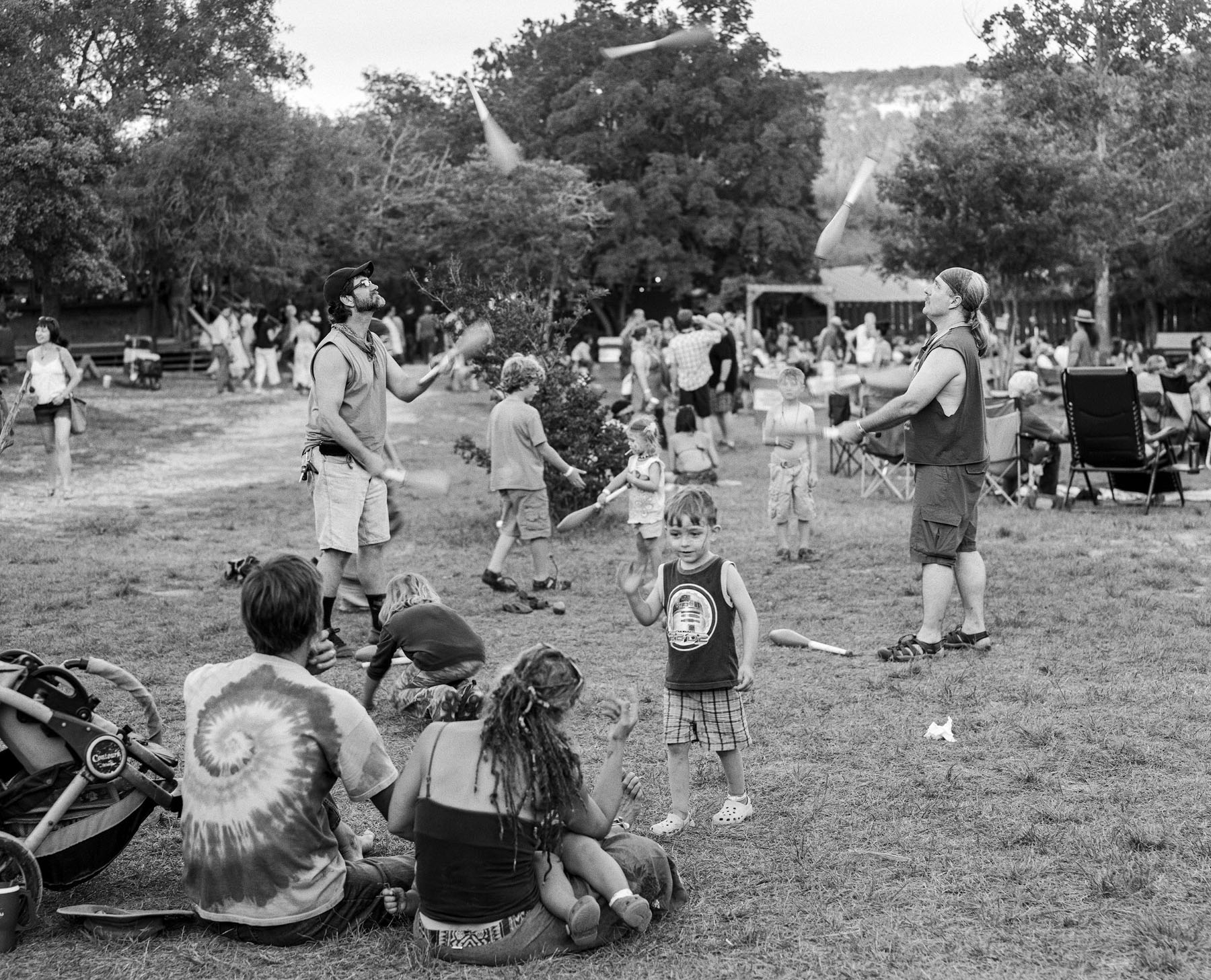 Two jugglers perform while a small crowd looks on