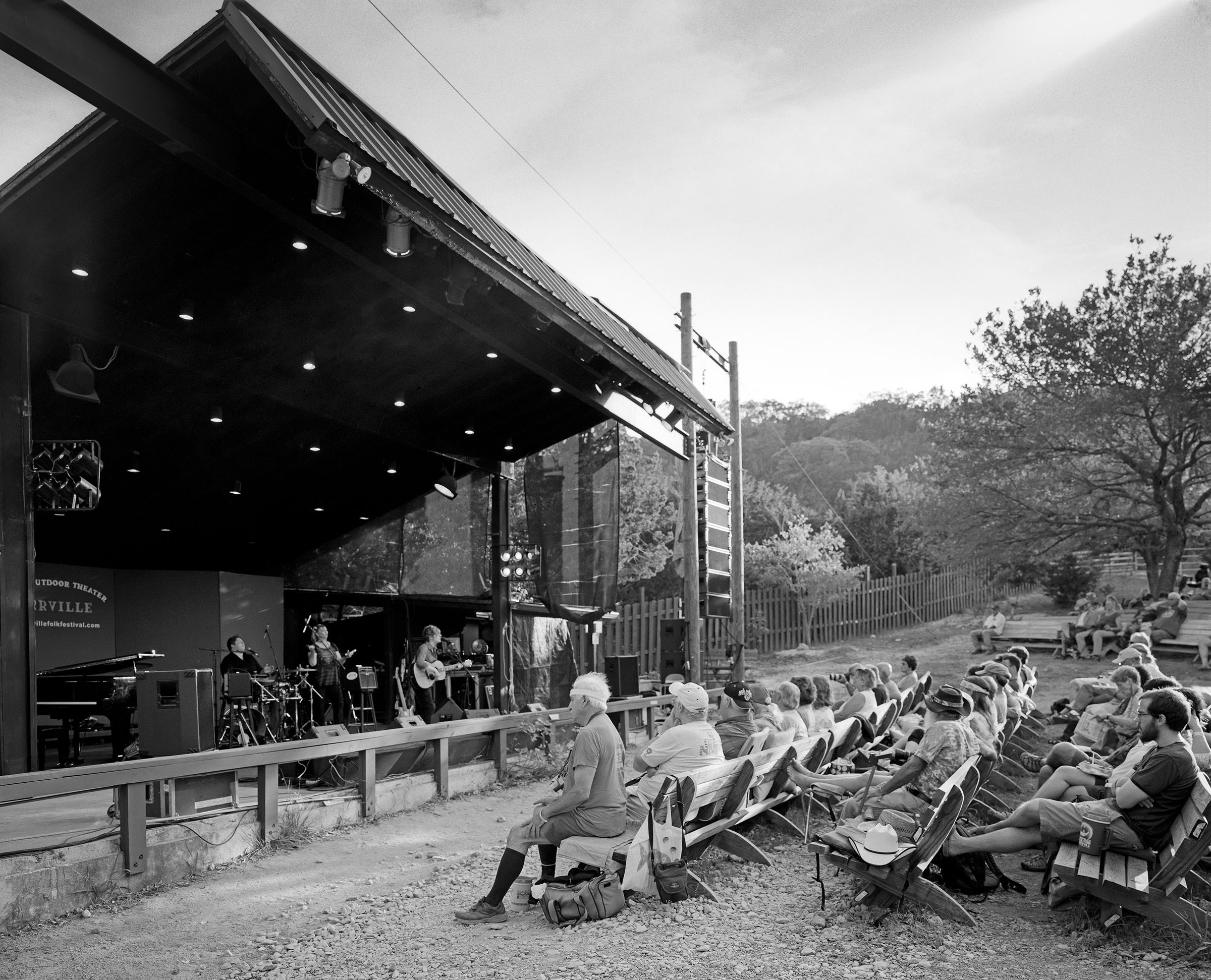 A large black main stage in front of a small gathering of people in a field