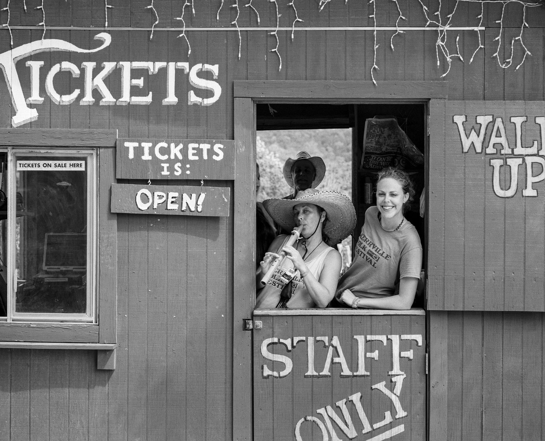 Two people lean out of a window reading "Tickets / Open/ Staff only"