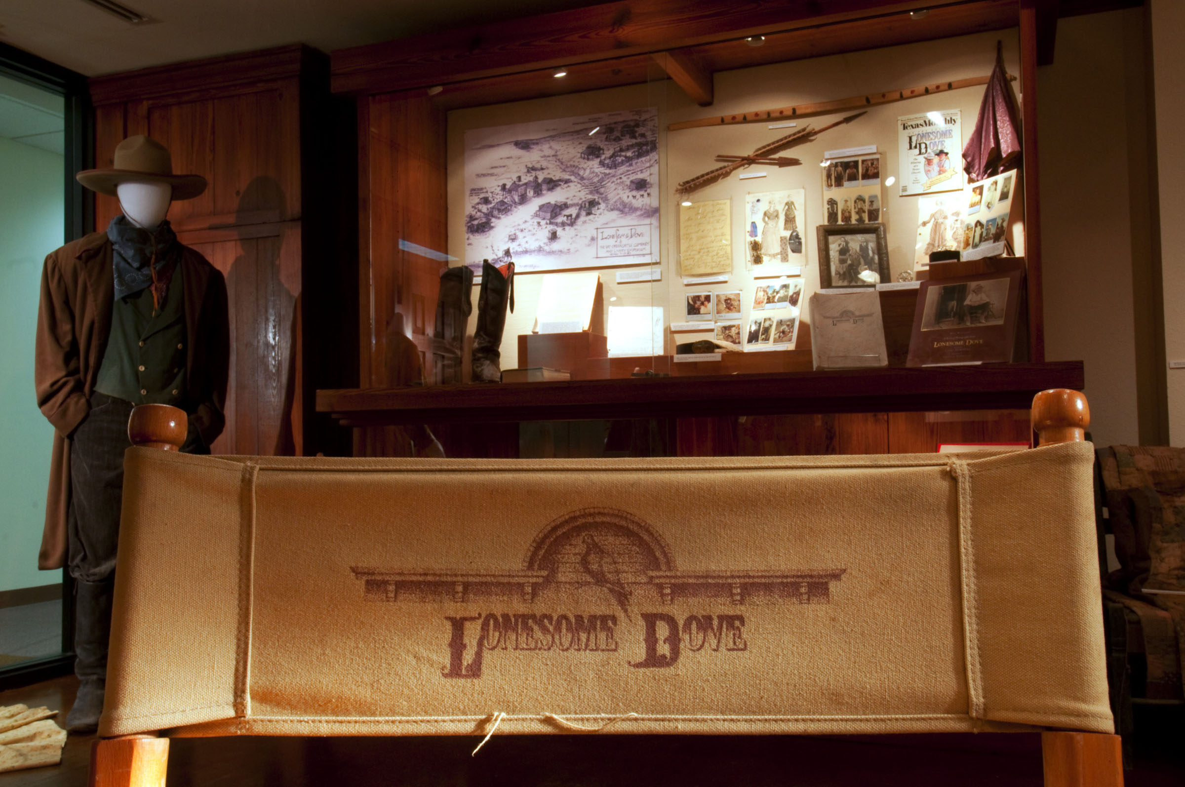 A collection of Lonesome Dove artifacts including a chair, clothes and more on display in a museum