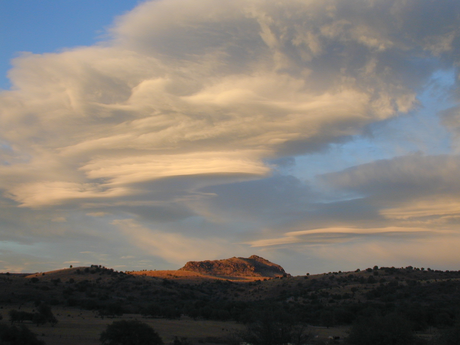 A white cloud and blue sky over a red rock