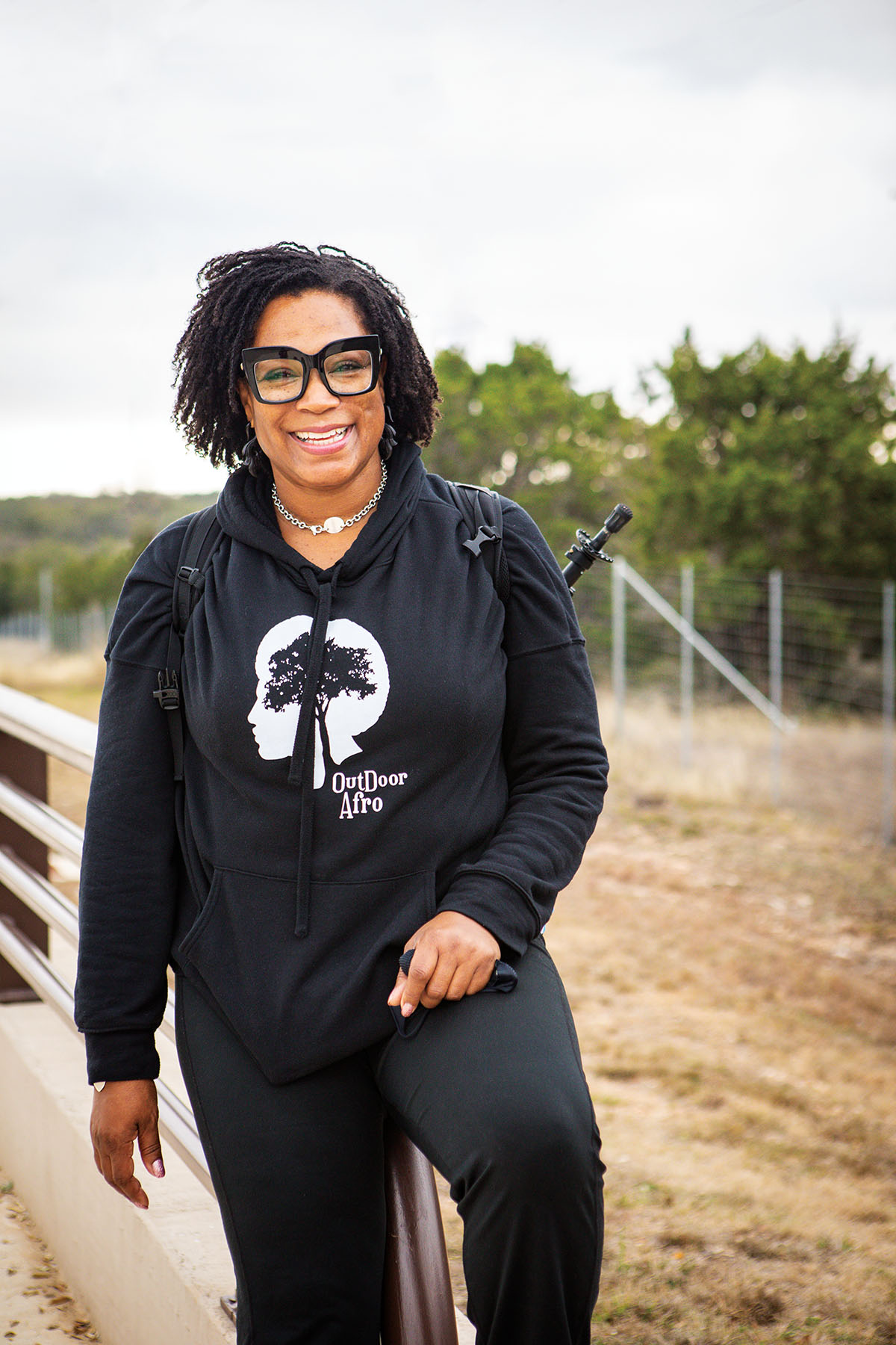 A woman in a black sweatshirt poses on a trail