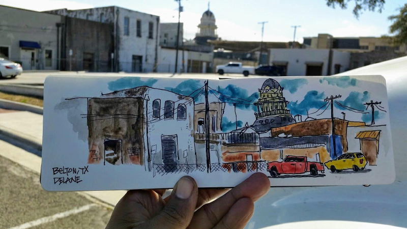 The artist's photo of him holding his postcard-size watercolor rendering of downtown Belton, comparing it to the area he captured. Photo courtesy Tony Delane Artwork.