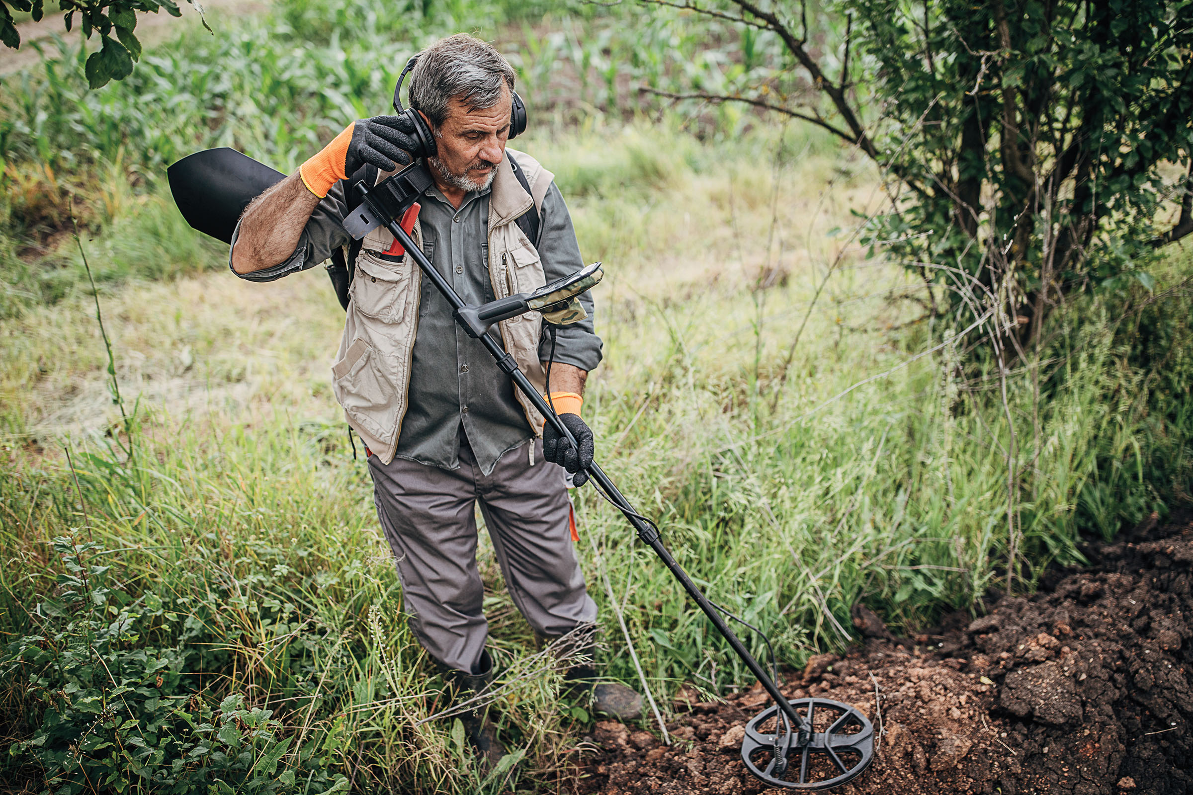 A man uses a metal detector in a green and brown field