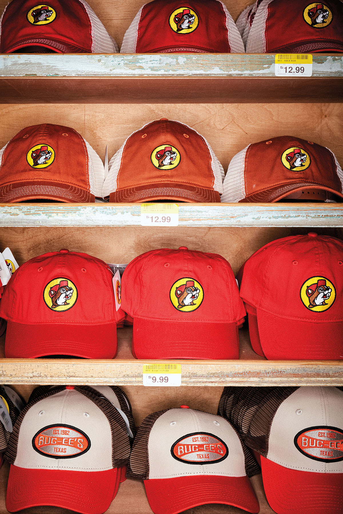 A collection of brown, red and white baseball hats featuring Buc-ee beaver