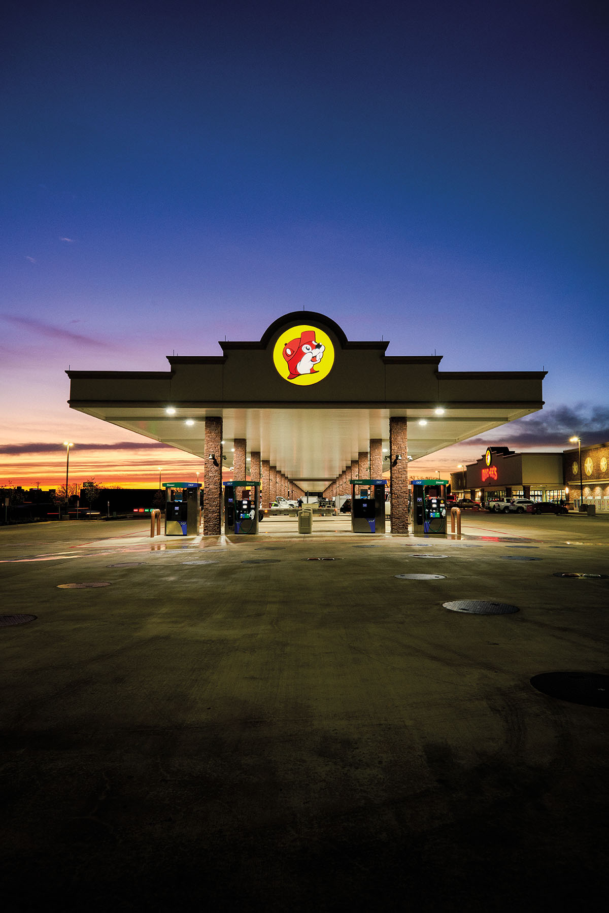 A purple and black night sky behind the glowing gas pumps at Buc-ees