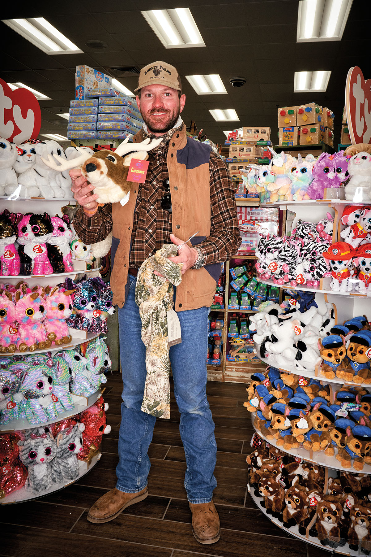 A man stands inside Buc-ees holding a stuffed deer mount, complete with antlers