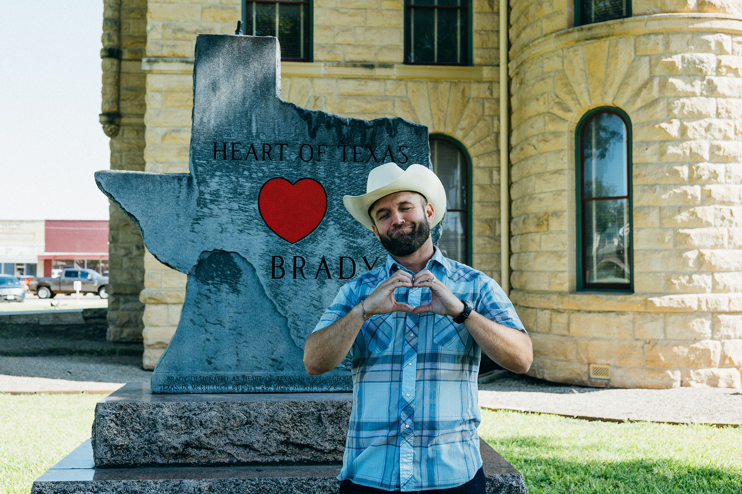 Chet Garner stands with his hands in the shape of a heart in front of a Texas-shaped sculpture