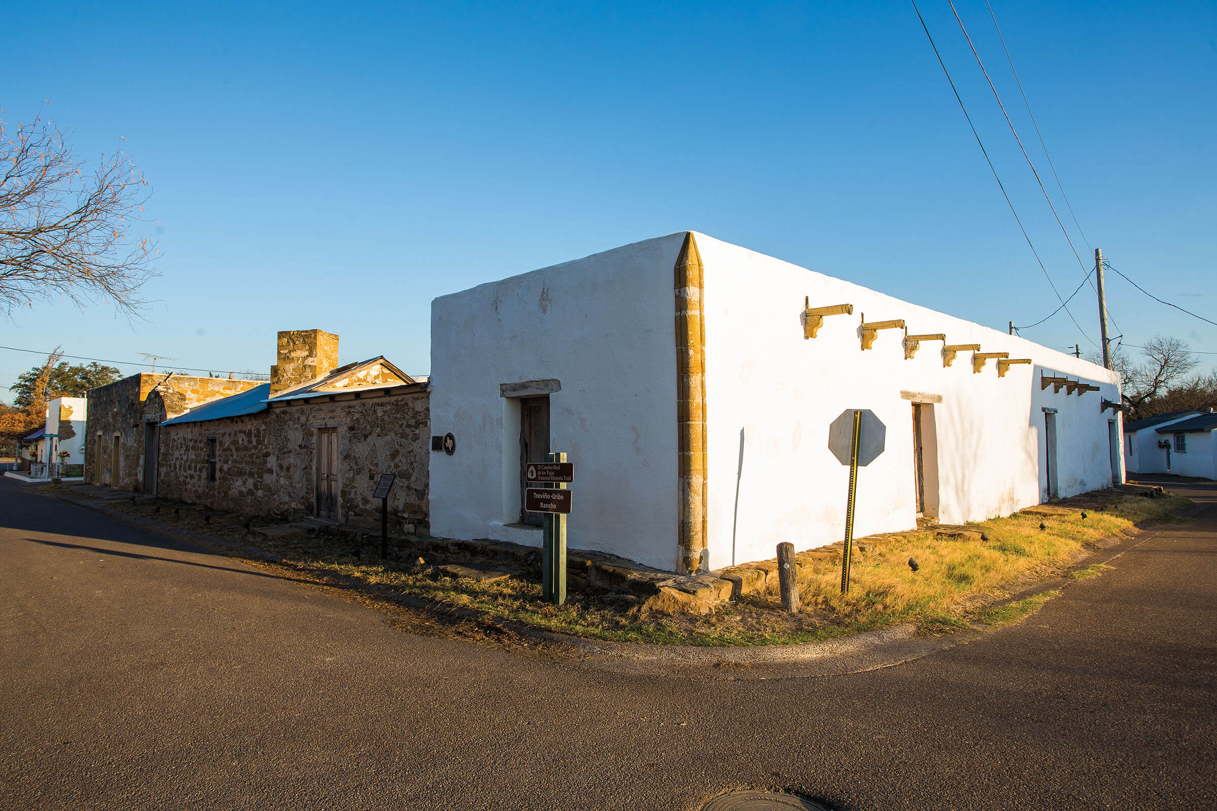 The white adobe facade of a building on a desert street