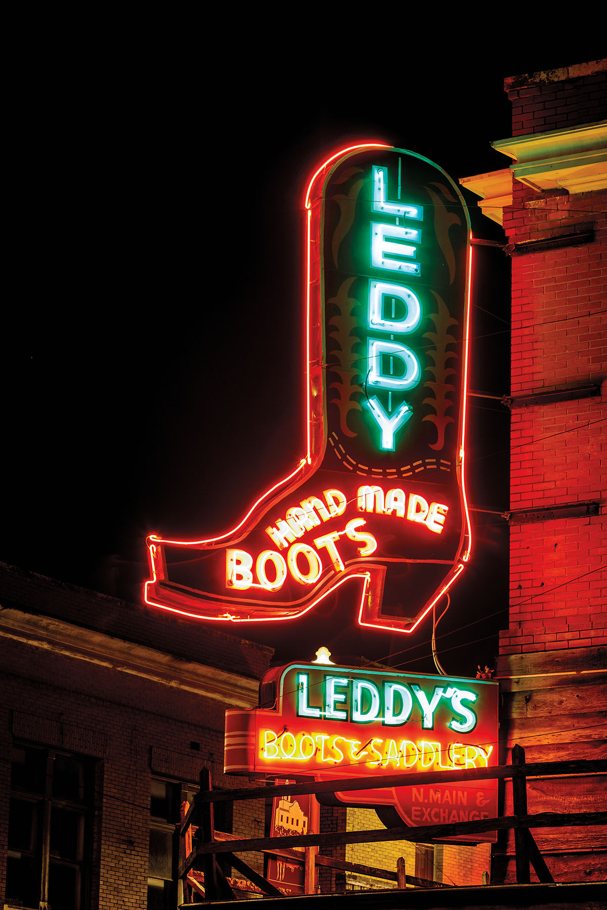 A green and red glowing neon sign reading "Leddy Hand-Made Boots"