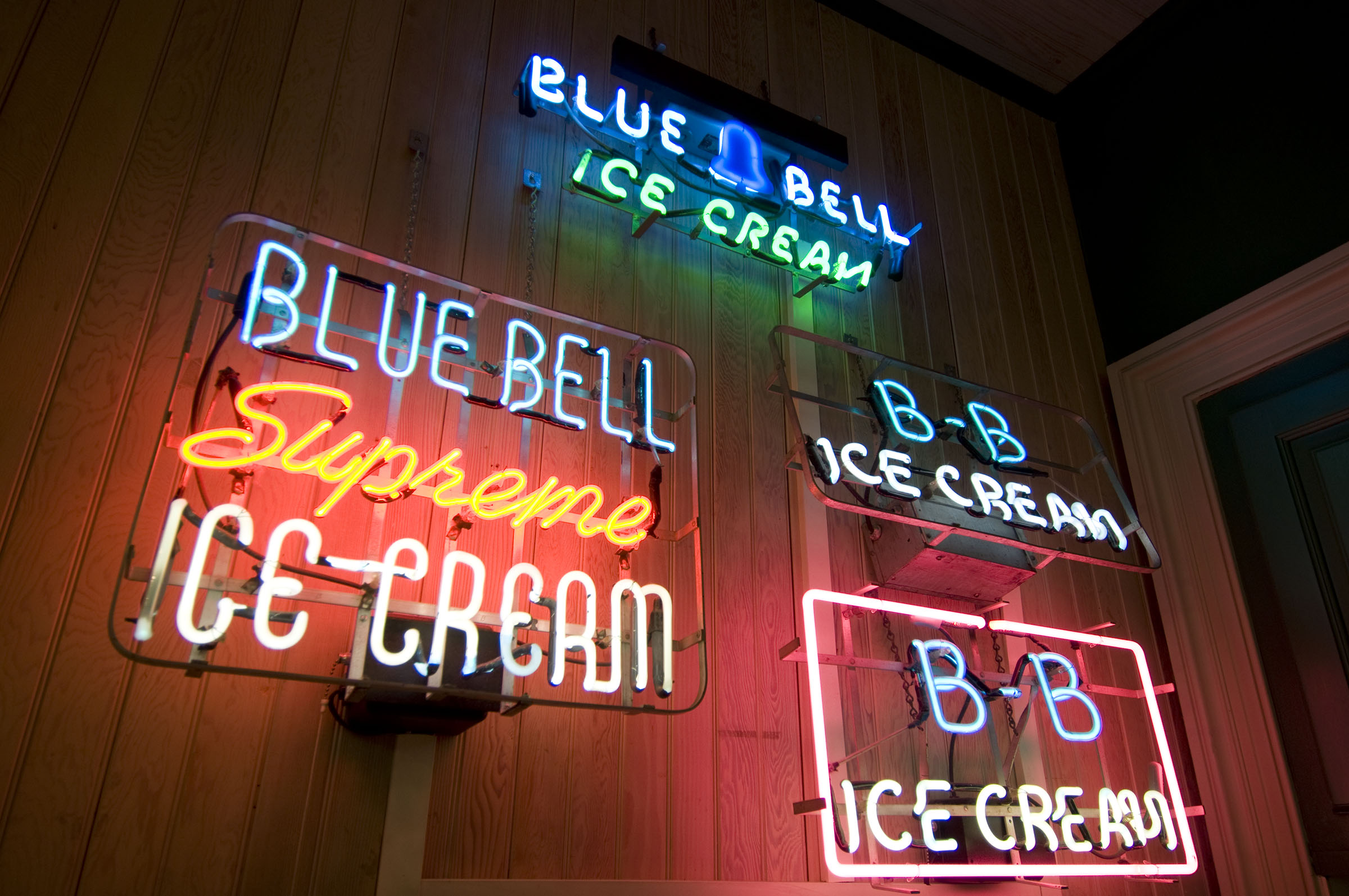Neon signs reading "Blue Bell Supreme Ice Cream" and "Blue Bell Ice Cream" adorn a wall