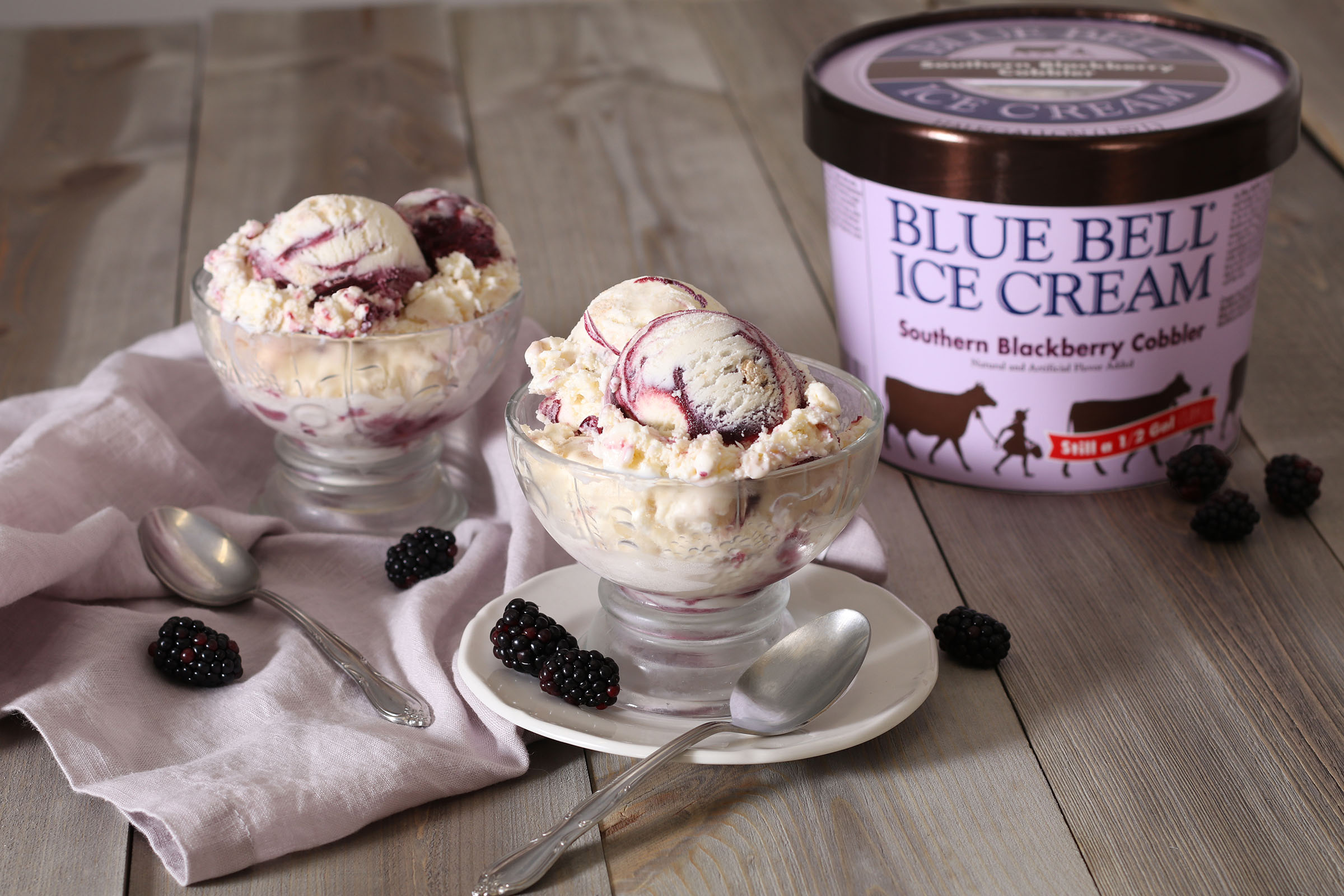Two dishes of Southern Blackberry Cobbler ice cream next to a light purple half gallon container