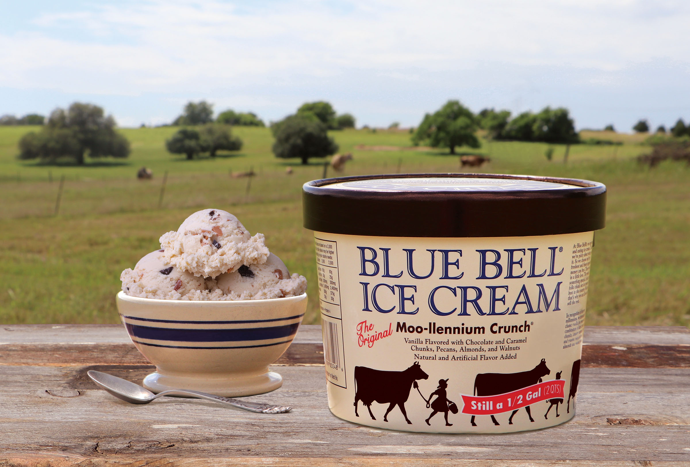 A half-gallon of Blue Bell  Moo-llennium Crunch ice cream next to a scoop in a dish