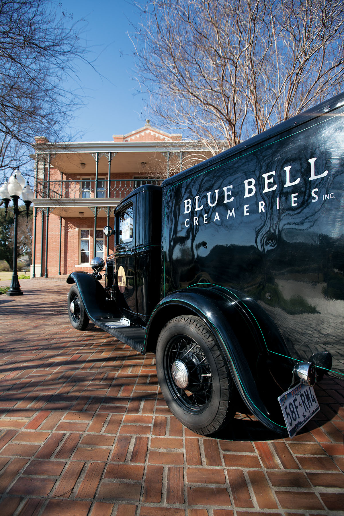 An old-fashioned black truck reading "Blue Bell Creameries" parked outside of the headquarters