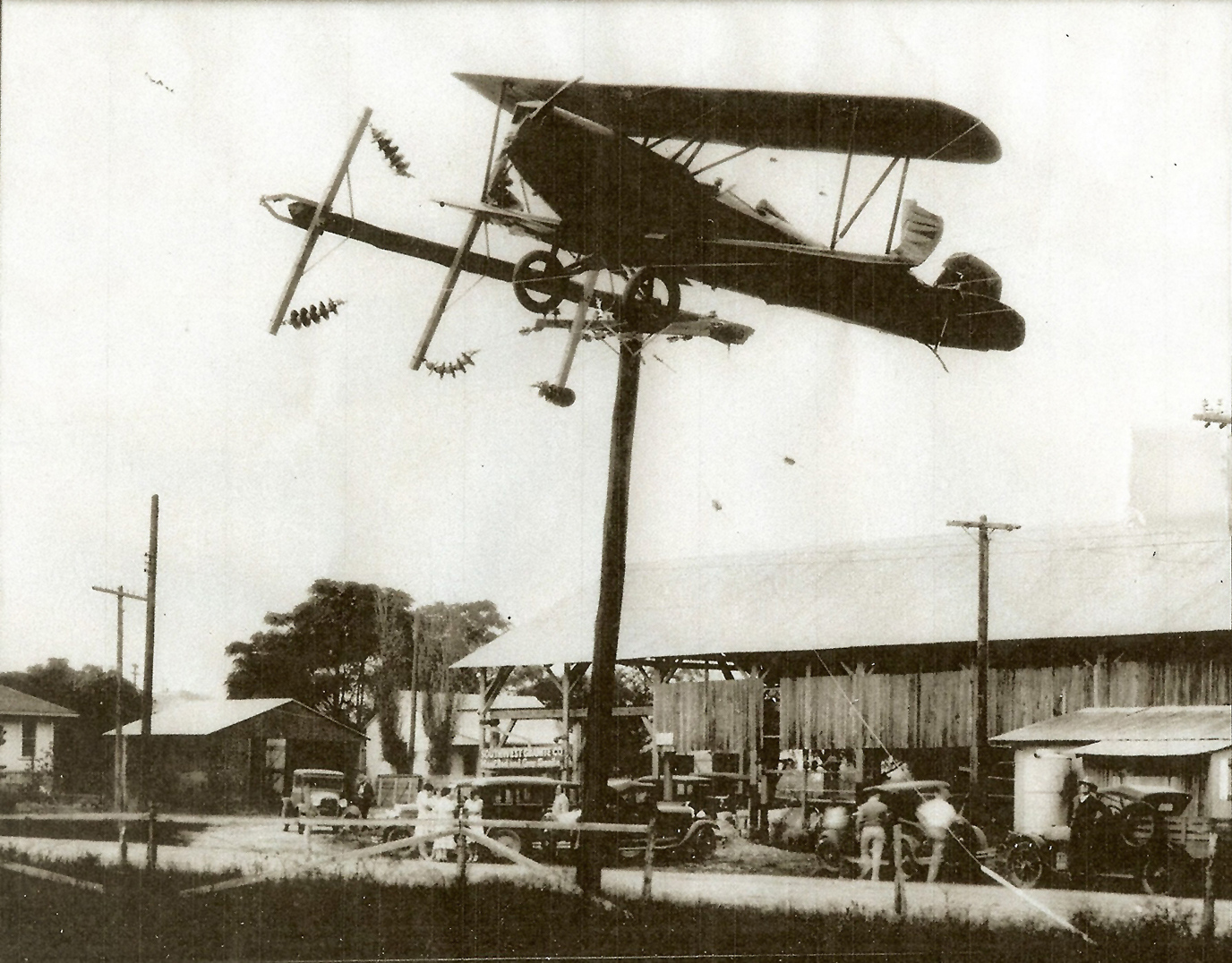 A sepia image of a plane upside down on a pole